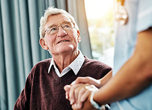 Nurse holding the hand of an elderly man