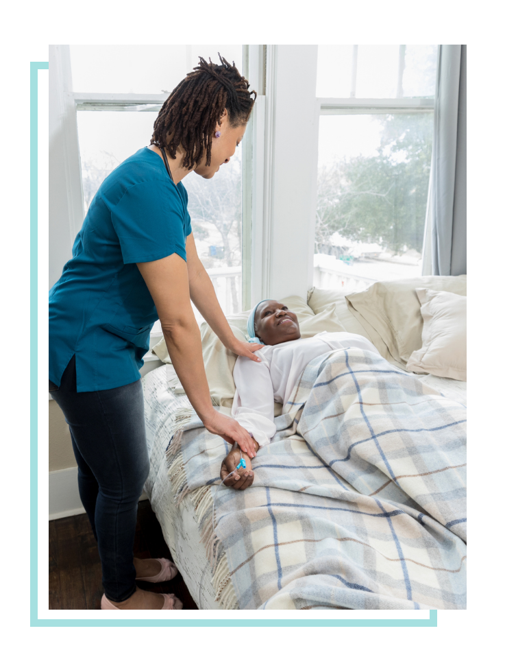 Female hospice care worker checking on a female patient in bed