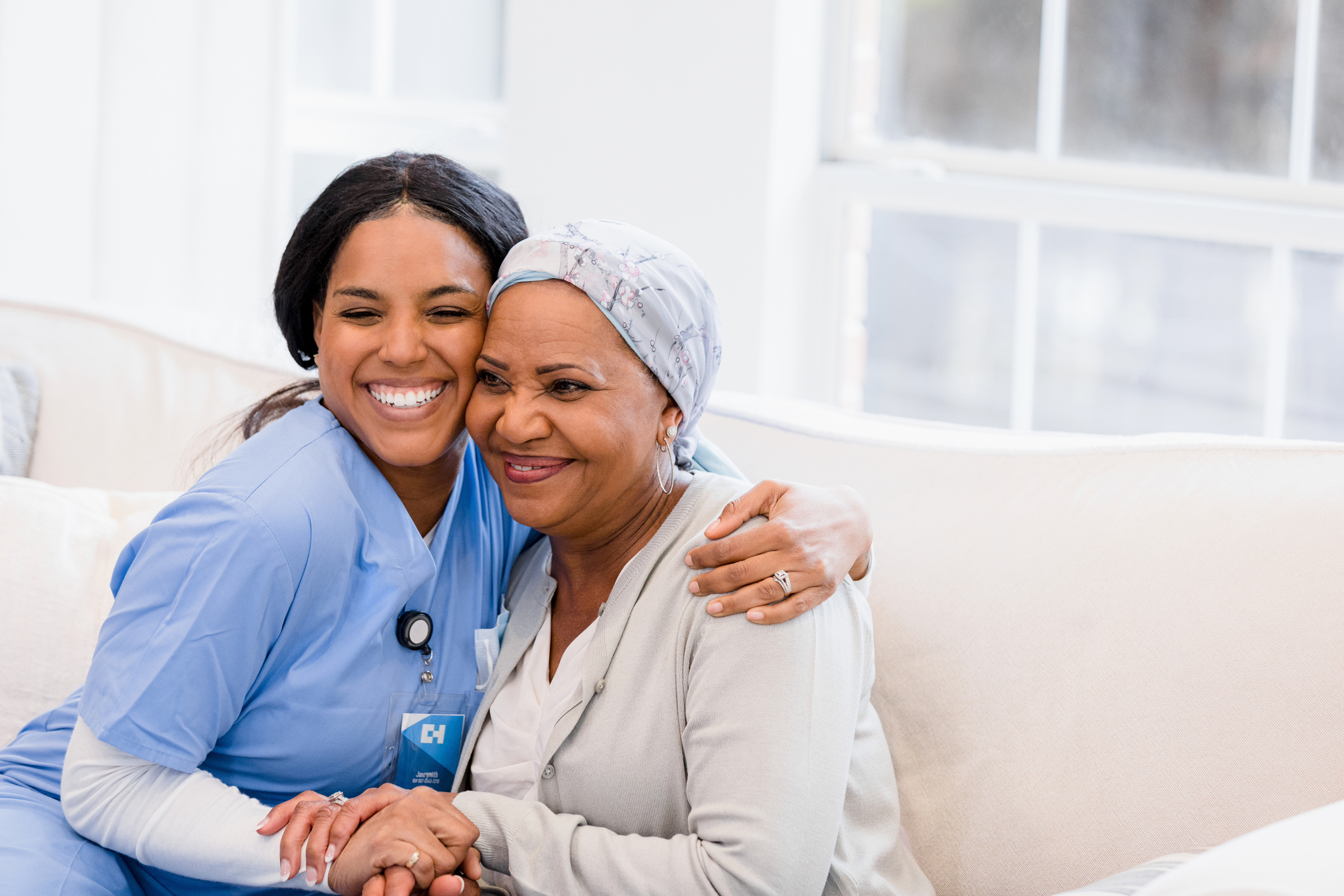 Home health care nurse embraces her patient at home.