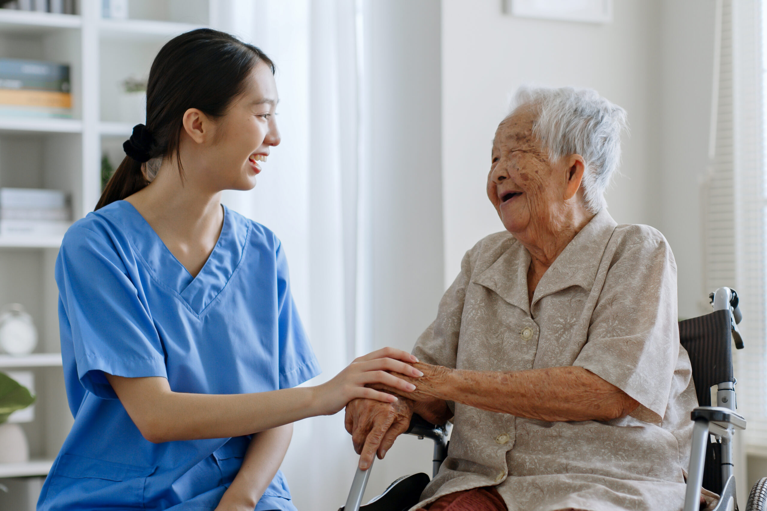 Young Asian hospice nurse, talking with senior Asian woman at home