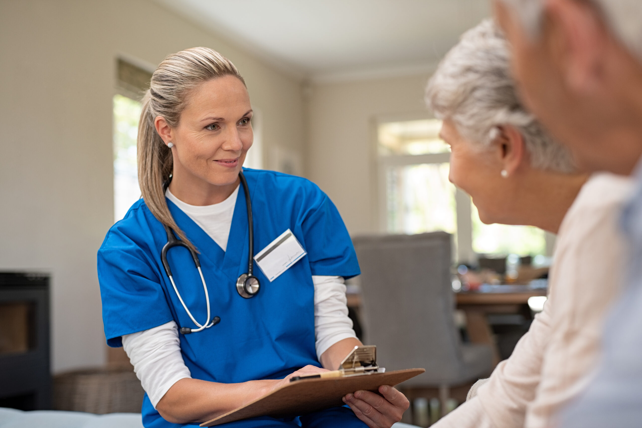 Happy nurse talking to senior patients in about the difference between home health care vs. home care