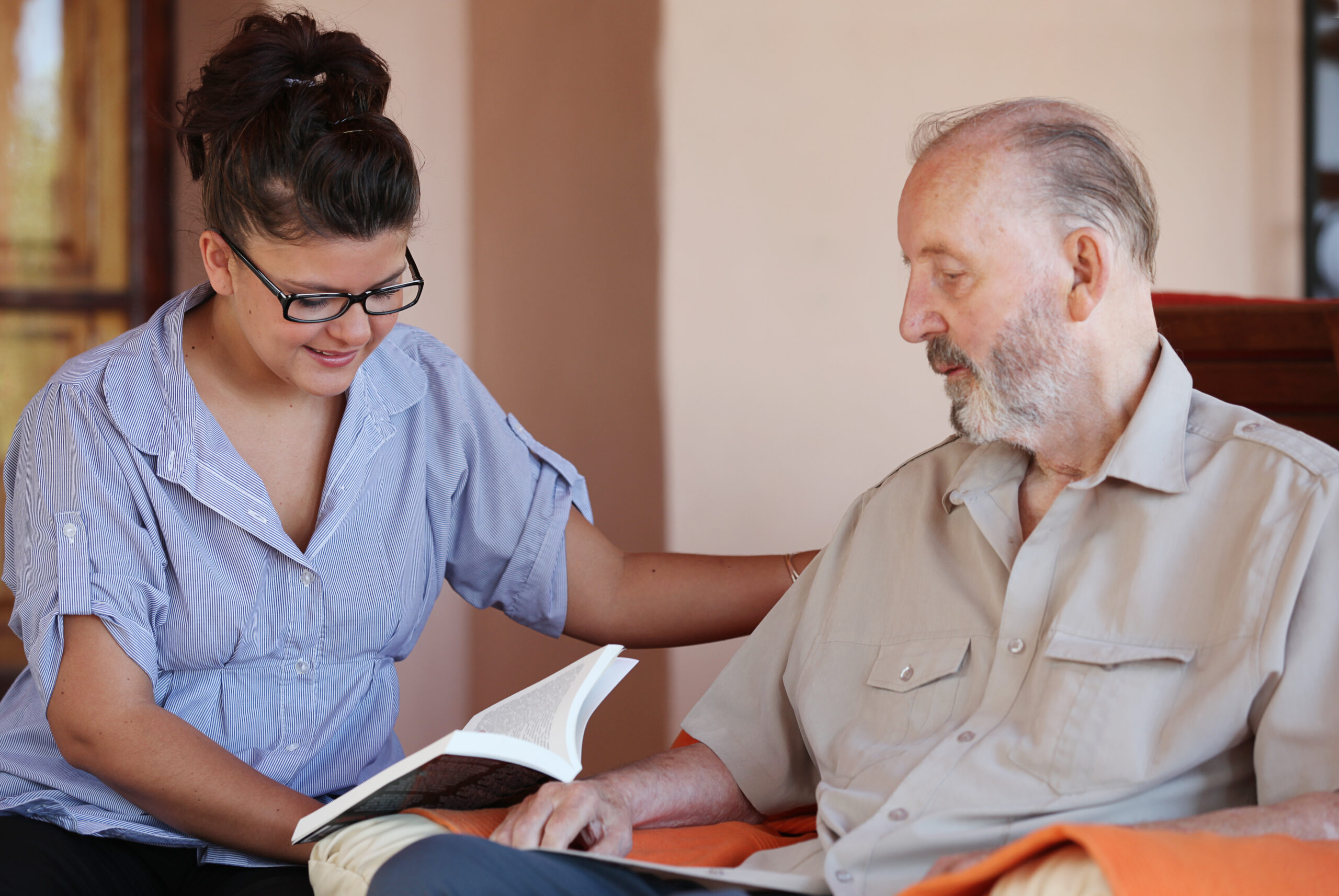 Volunteer reading a book to senior male patient